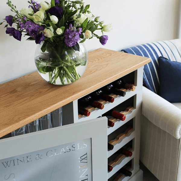 Floor standing unit with one side being an open wine rack with oak bottle accents, and the other being a glazed cupboard for glasses storage etched with the words wine and glasses