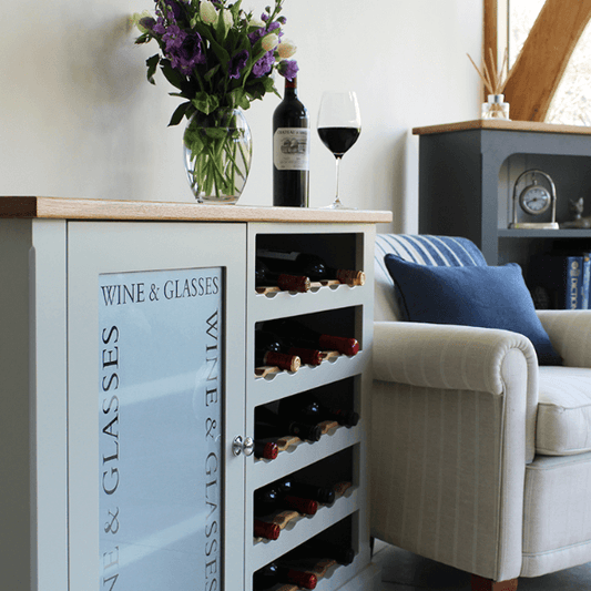 Floor standing unit with one side being an open wine rack with oak bottle accents, and the other being a glazed cupboard for glasses storage etched with the words wine and glasses.