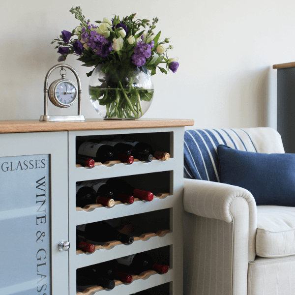 Floor standing unit with one side being an open wine rack with oak bottle accents, and the other being a glazed cupboard for glasses storage etched with the words wine and glasses